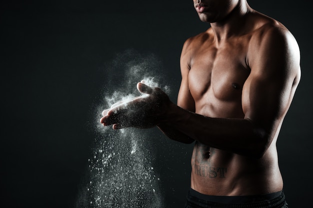 Image recadrée de bel homme de sport afro-américain se frottant les mains à la craie