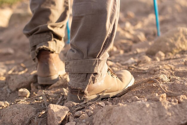 Image recadrée de bottes de randonneur. Personne en pantalon déchiré avec des bâtons spéciaux qui montent. Passe-temps, nature, concept d'activité de plein air