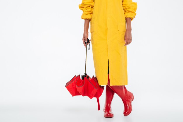 Image recadrée de femme africaine en imperméable avec parapluie