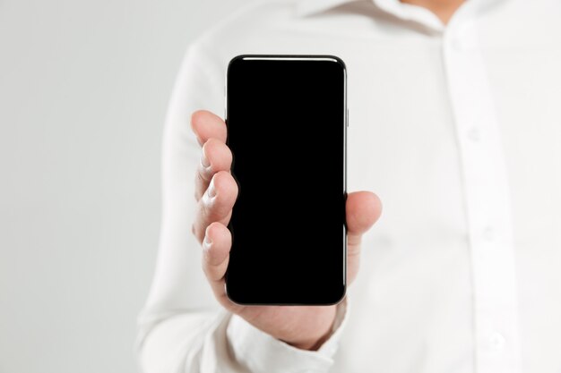 Image recadrée de jeune homme montrant l'écran du téléphone.