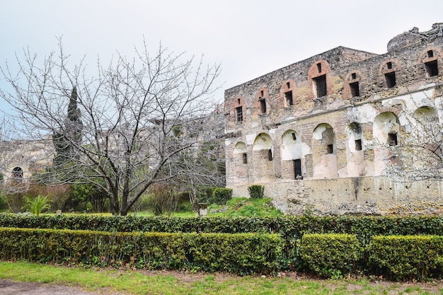 Image d'une ruine avec des haies au premier plan sous un ciel nuageux