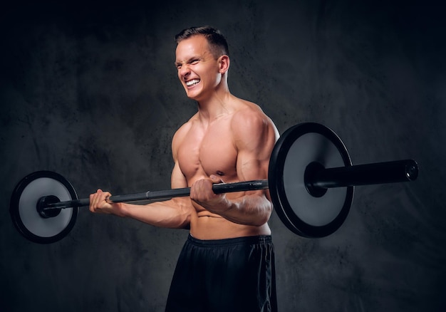 Image studio d'un homme musclé torse nu tenant une barre sur fond de vignette grise.