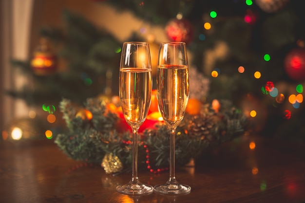Image Tonique De Deux Verres De Champagne Remplis Devant Une Couronne De Noël Avec Des Bougies Allumées Photo Premium