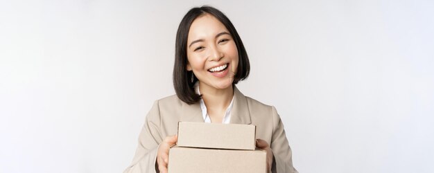 Image d'une vendeuse asiatique femme d'affaires donnant des boîtes avec commande livrée au client debout en costume sur fond blanc