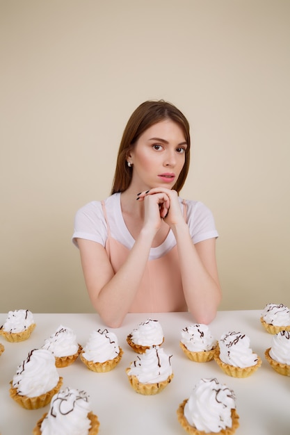 Image verticale de femme calme par la table avec des gâteaux