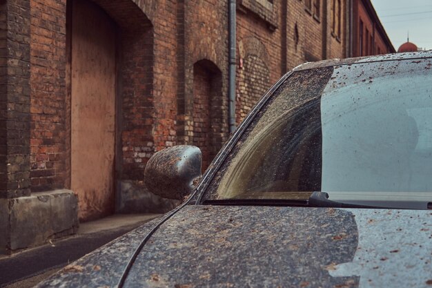 Image d'une voiture sale après un voyage hors route. Se dresse contre un mur de briques dans la vieille ville.