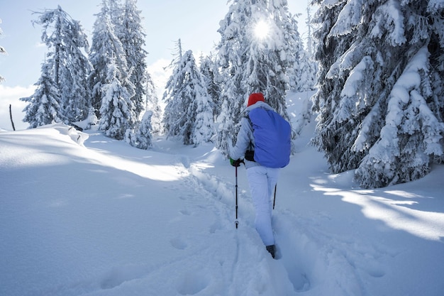 Images du dos d'un jeune randonneur avec un costume de ski blanc et un chapeau aux couleurs vives