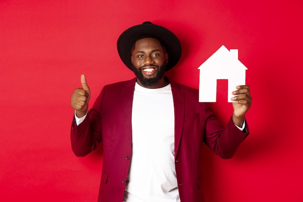 Immobilier. Homme barbu élégant montrant la maison maket