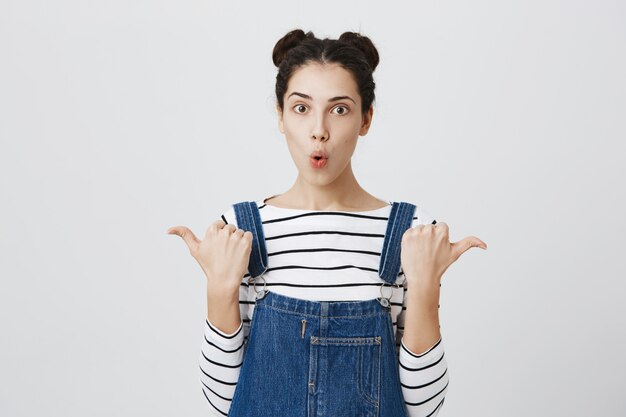 Impressionné femme pointant sur le côté, l'air étonné