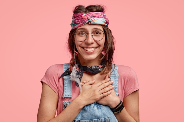 Impressionné heureux femme hippie caucasienne garde les deux mains sur la poitrine