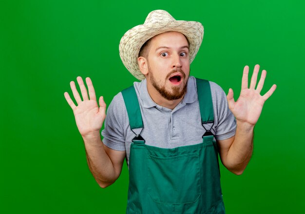 Impressionné jeune beau jardinier slave en uniforme et chapeau à la recherche de mains vides