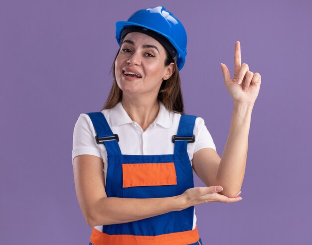 Impressionné jeune femme constructeur en points uniformes à up isolé sur mur violet