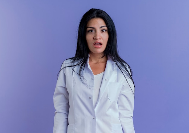 Impressionné jeune femme médecin portant une robe médicale à la recherche