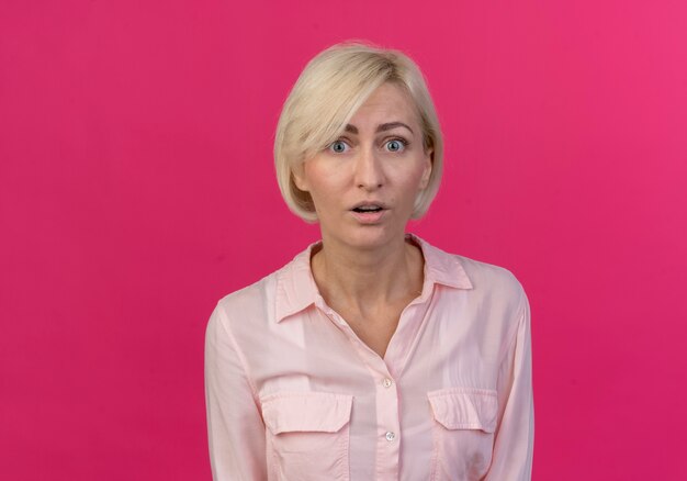 Impressionné jeune femme slave blonde debout et regardant la caméra isolée sur fond rose avec copie espace