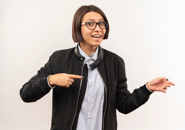 Impressionné jeune fille de centre d'appels portant des lunettes pointant sur le côté isolé sur blanc