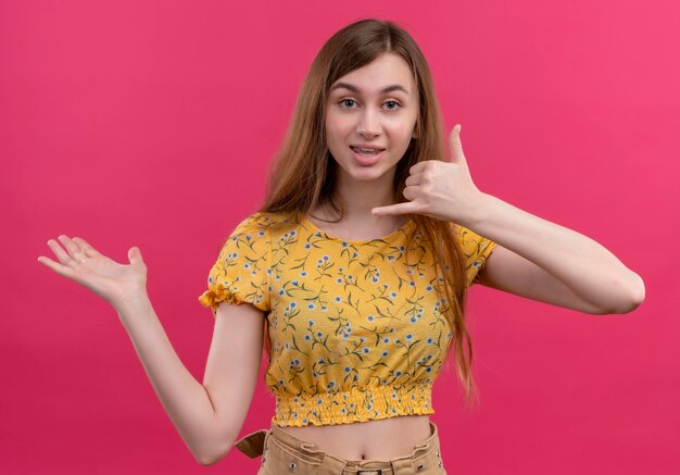 Impressionné jeune fille faisant le geste d'appel et montrant la main vide sur l'espace rose isolé