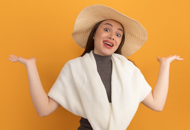 Impressionné jeune jolie femme portant un chapeau de plage montrant les mains vides