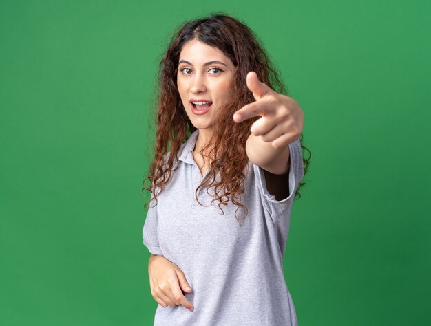 Impressionné jeune jolie fille caucasienne debout dans la vue de profil regardant et pointant isolé sur un mur vert avec espace de copie