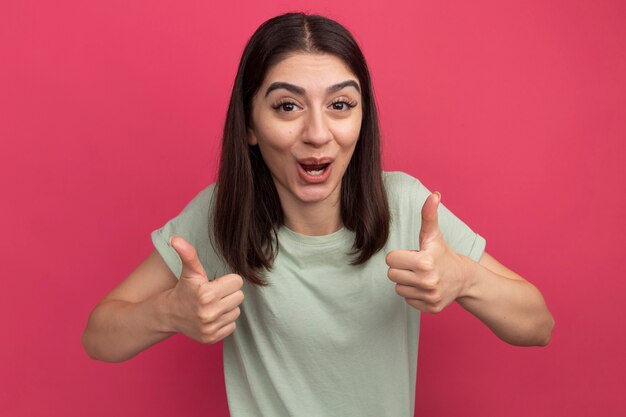 Impressionné jeune jolie fille caucasienne montrant les pouces vers le haut