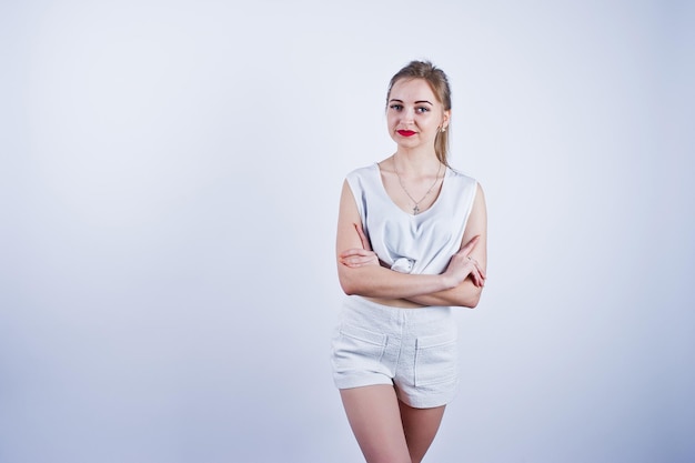 Incroyable ajustement corps sexy brunette caucasienne fille posant au studio sur fond blanc sur short et haut