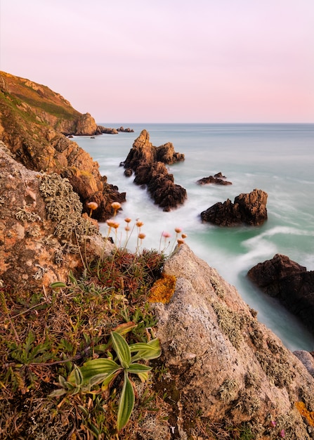 Incroyable coup d'une plage rocheuse dans la baie de Jaonnet sur un coucher de soleil