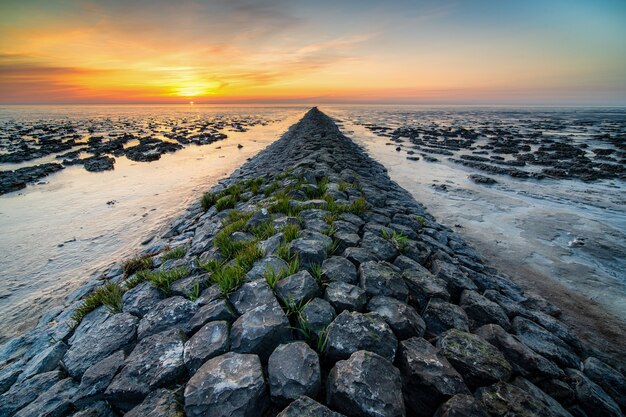 Incroyable coup d'une plage rocheuse sur la distance du coucher du soleil