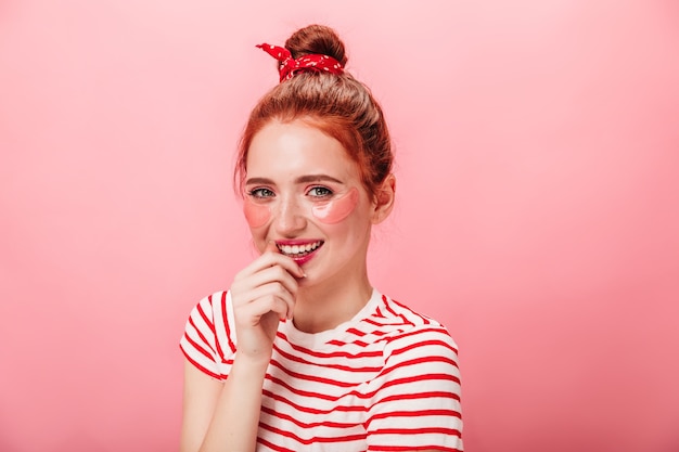 Incroyable Femme Caucasienne Posant Avec Le Sourire Pendant Le Traitement De La Peau. Photo De Studio De Joyeuse Fille Blanche Avec Des Pansements Oculaires.