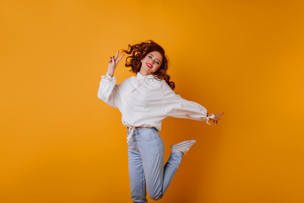 Incroyable femme mince qui s'amuse. Fille rousse en chemisier blanc sautant et souriant.