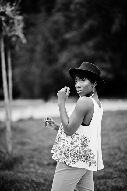 Incroyable femme modèle afro-américaine en pantalon vert et chapeau noir posé au parc