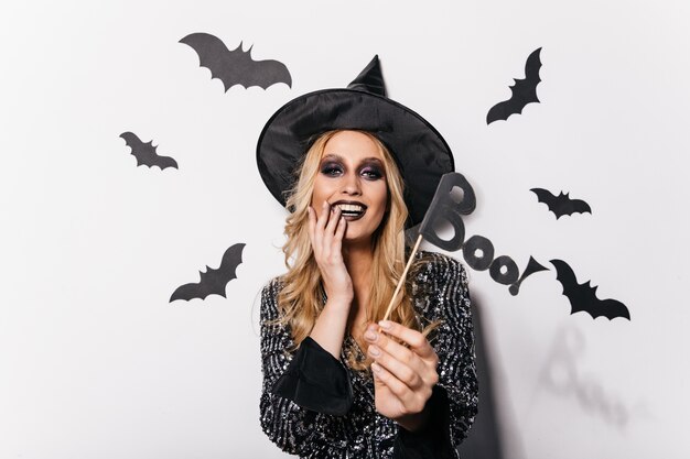 Incroyable jeune femme posant à Halloween avec des chauves-souris. Jolie fille blonde appréciant le carnaval.