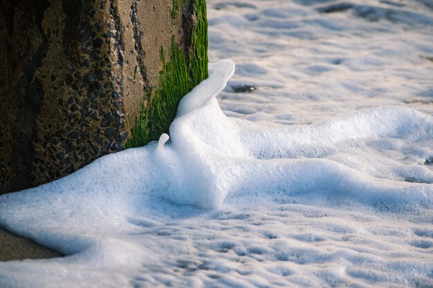 Incroyable photo de vagues de la mer frappant une colonne de pierre recouverte de mousse et faisant des éclaboussures