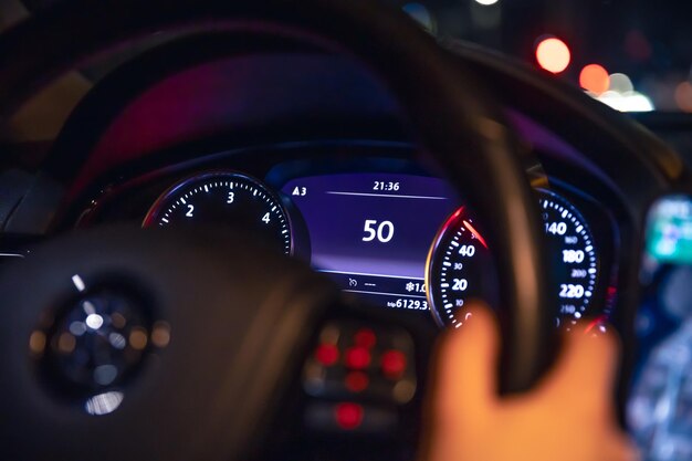 Indication de vitesse et mains féminines sur le volant d'une voiture la nuit