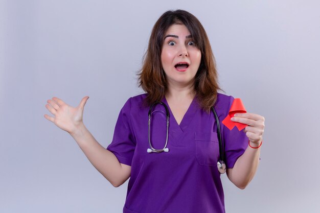 Infirmière d'âge moyen en uniforme et avec stéthoscope tenant un ruban rouge un symbole de la lutte contre le sida