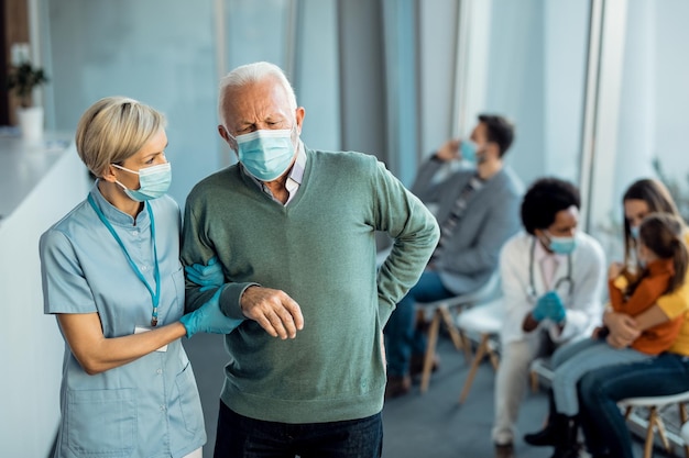 Infirmière attentionnée aidant un homme âgé qui est venu faire un rendez-vous médical à la clinique