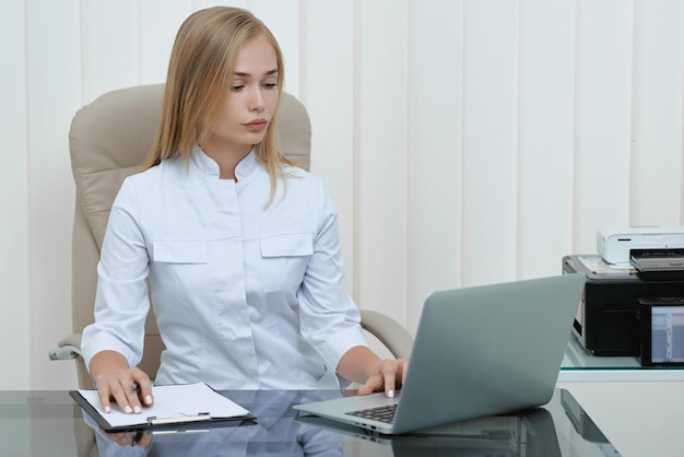 Infirmière blonde assise à l'hôpital et travaillant