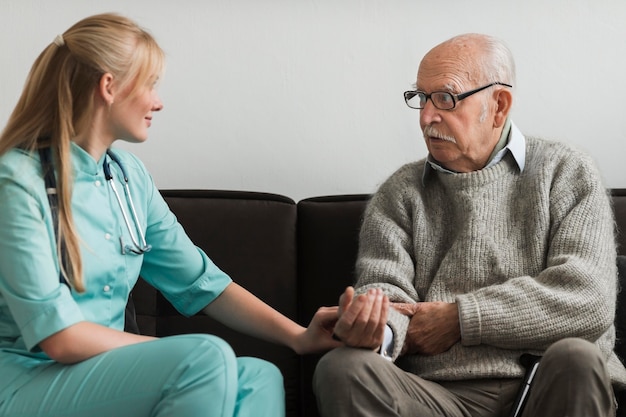 Infirmière consoler le vieil homme dans une maison de soins infirmiers