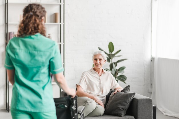 Infirmière, à, fauteuil roulant, debout, ion, front, de, heureux, femme, patient