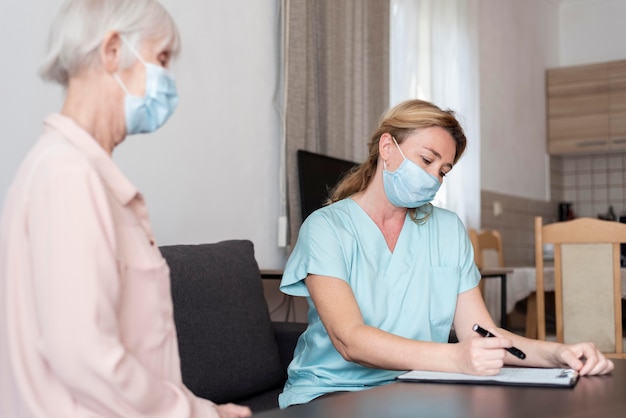 Infirmière lors d'un contrôle avec une femme plus âgée à la maison de soins infirmiers