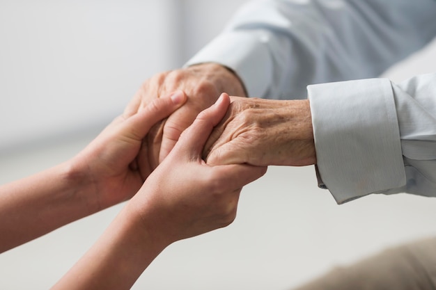 Infirmière tenant les mains de l'homme senior pour sympathie