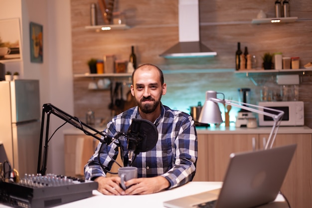 Influenceur tenant une tasse de café et enregistrant un podcast en home studio