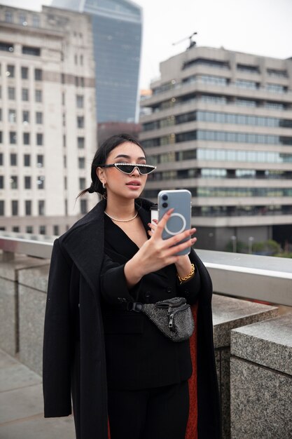 Influenceuse prenant un selfie avec son smartphone sur un pont