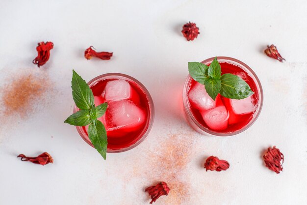 Infusion froide de thé d'hibiscus avec de la glace et des feuilles de basilic.