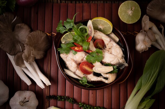 Infusion de poisson bouilli aux tomates, champignons, coriandre, ciboule et citronnelle dans un bol