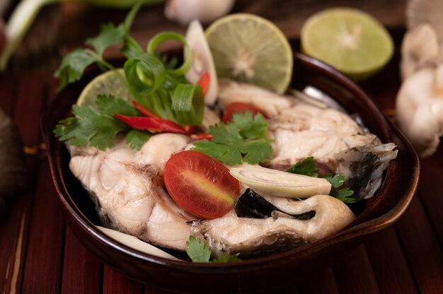 Infusion de poisson bouilli aux tomates, champignons, coriandre, ciboule et citronnelle dans un bol