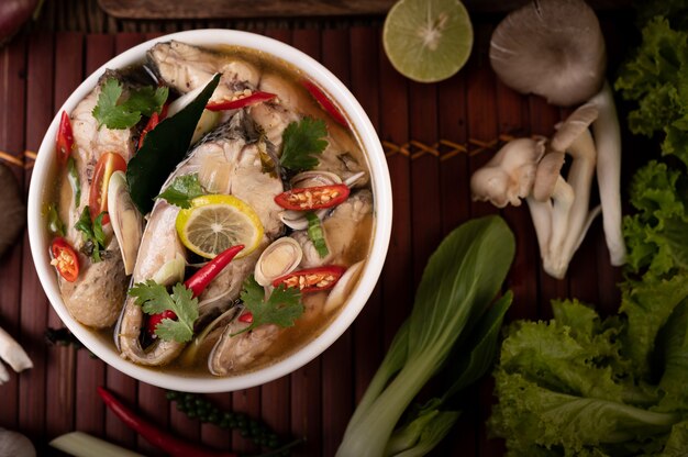 Infusion de poisson bouilli aux tomates, champignons, coriandre, ciboule et citronnelle dans un bol