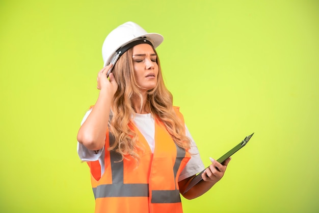 Ingénieur en casque blanc et équipement tenant la liste de contrôle et rêver.