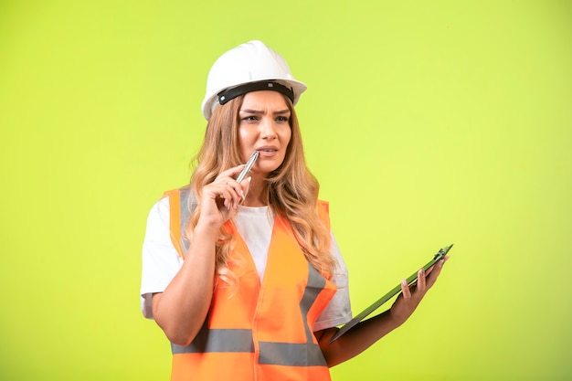 Ingénieur en casque blanc et équipement tenant la liste de contrôle et se sent douteux.