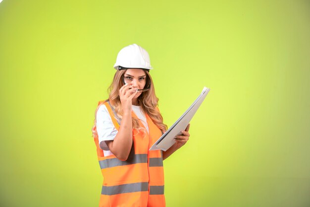 Ingénieur en casque et équipement tenant le plan de projet et portant ses lunettes.