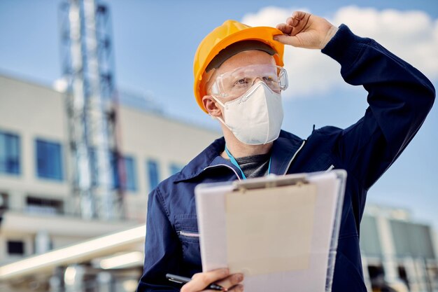 Ingénieur civil albinos avec masque facial inspectant le projet en cours sur le chantier de construction