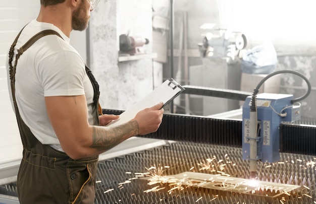 Ingénieur contrôlant la découpe laser métal plasma.